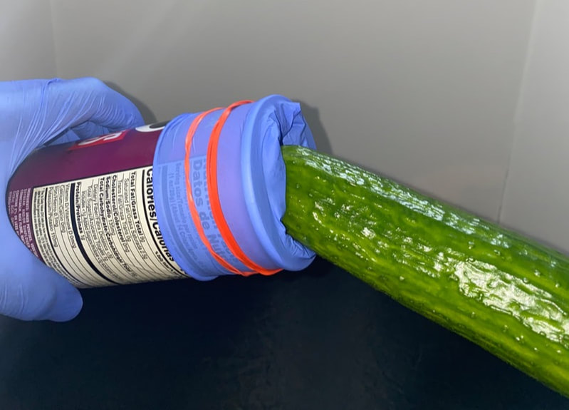 A diy sex toy demonstration using a cucumber and a can of Pringles with a latex glove and rubber bands around it.